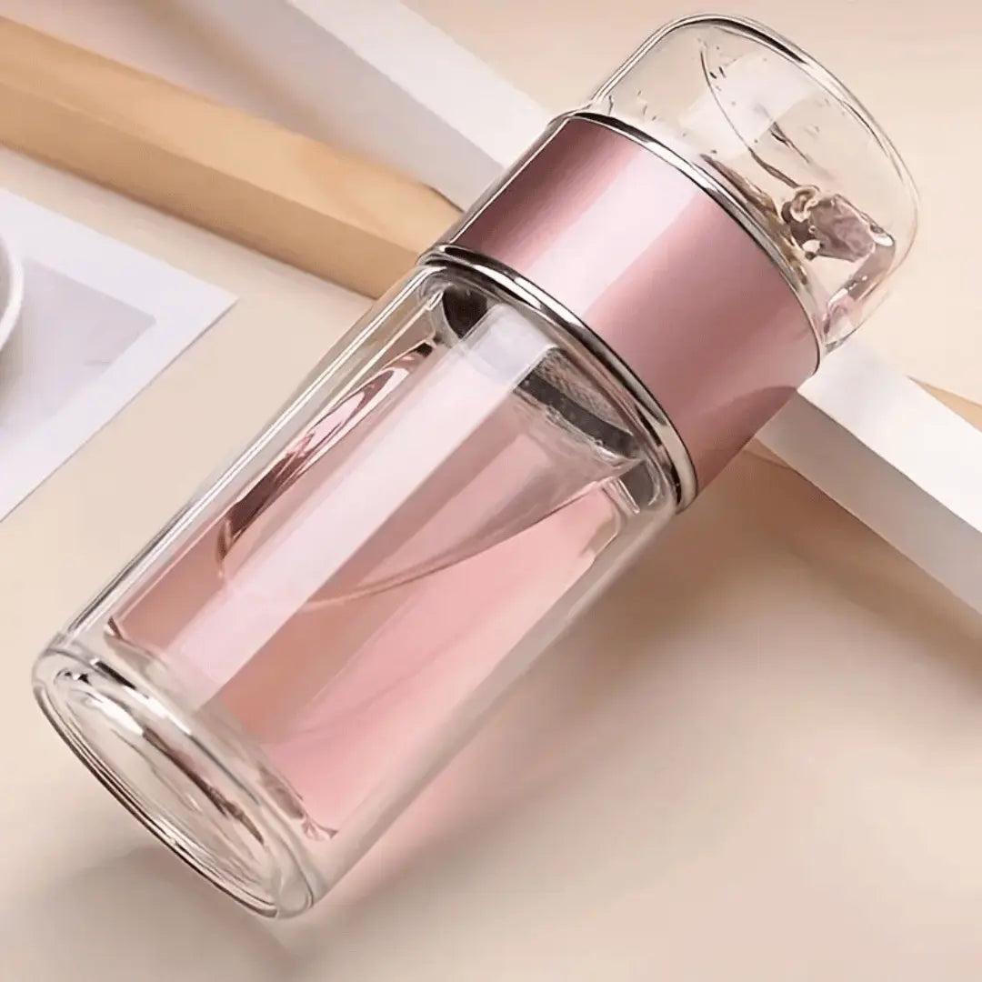 A sleek, double-walled glass tea infuser bottle with a black lid, shown with tea leaves on the top chamber and liquid in the bottom chamber.