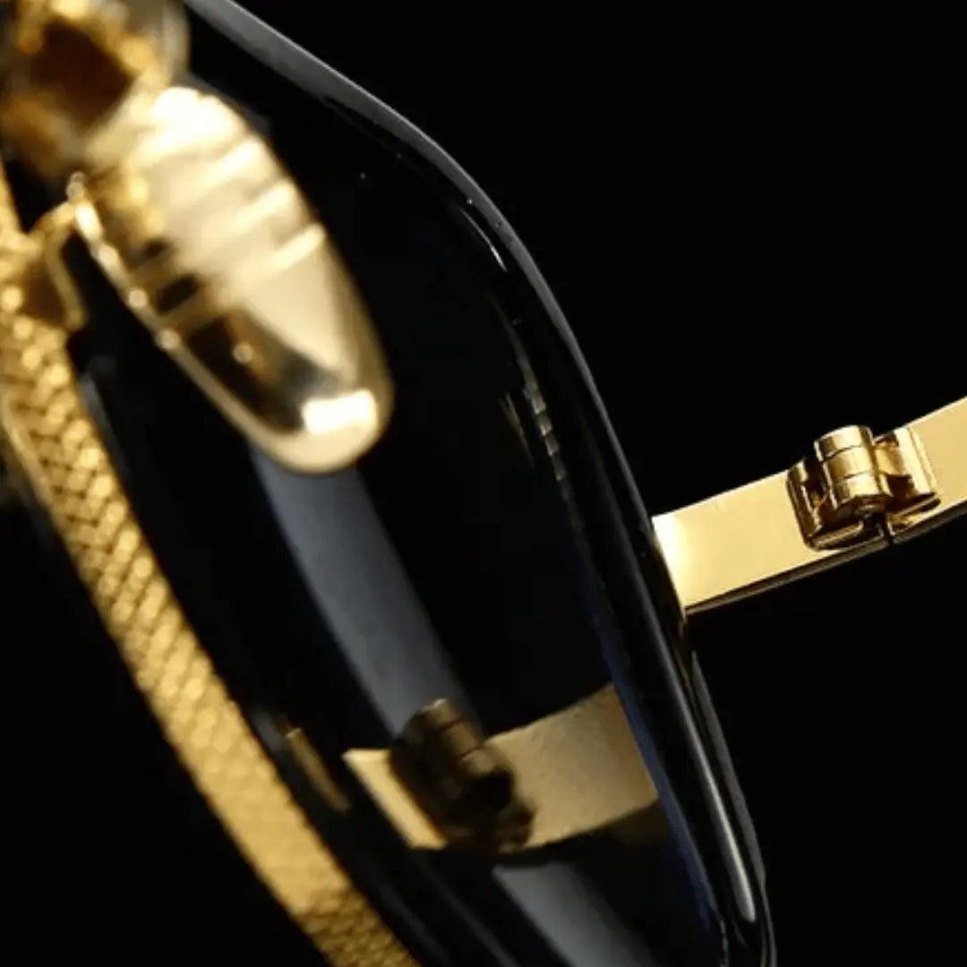 A pair of aviator-style sunglasses with black plastic frames and gold metal accents. The lenses appear to be dark tinted.