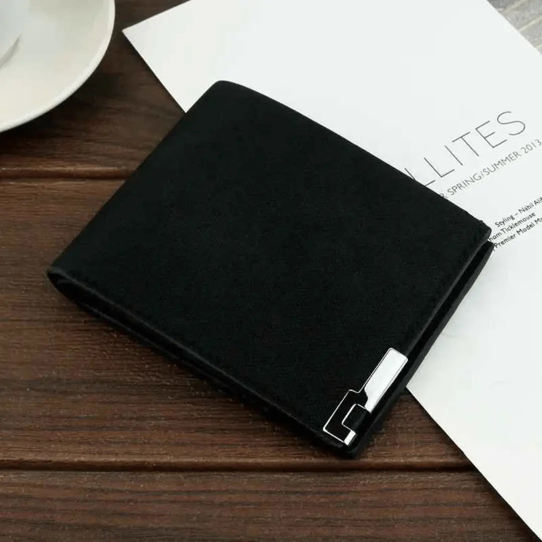 A sleek black wallet placed on a wooden surface, with a part of a white card and a wooden texture visible in the background.