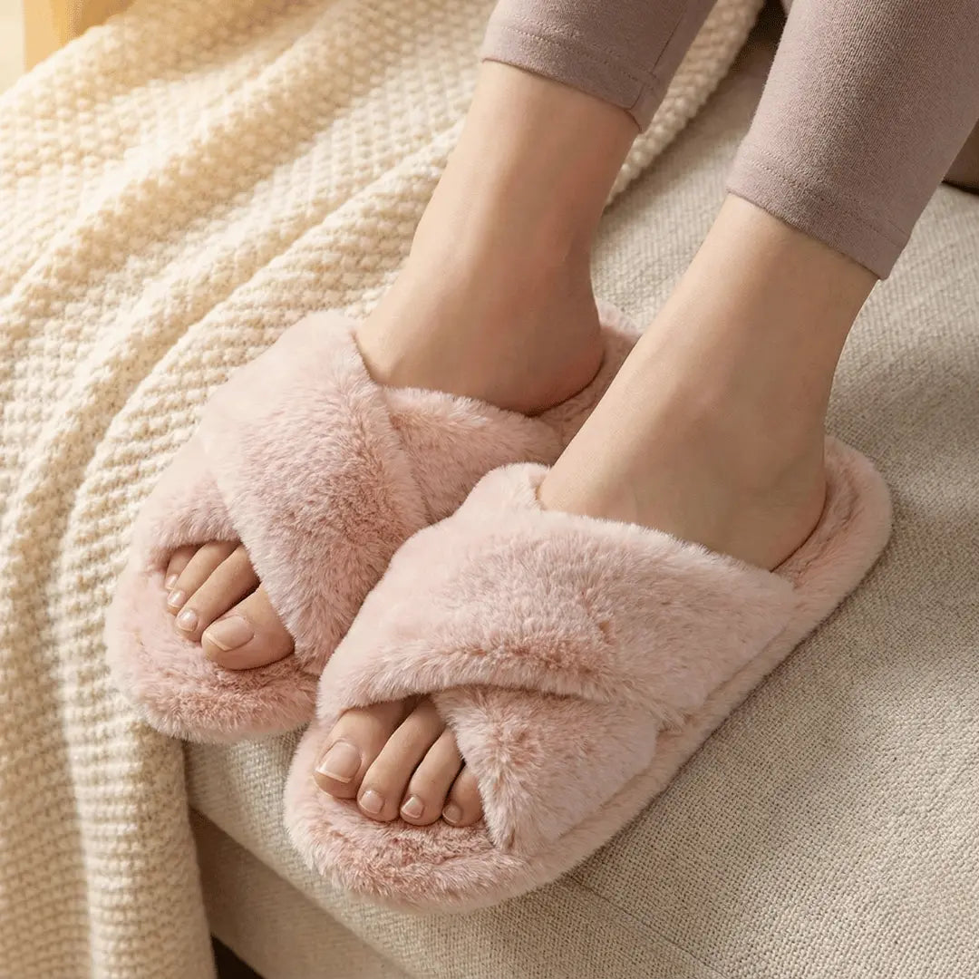 Pink fuzzy slippers worn indoors on a soft surface
