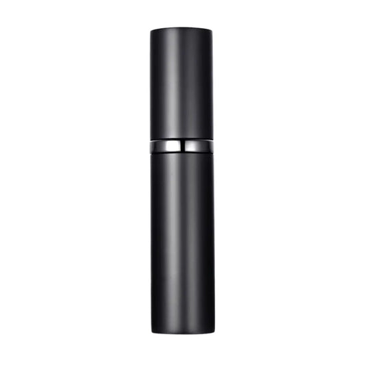 A hand holding a black travel-size perfume atomizer with a fine spray of perfume, highlighting the product's capability to spray without water drops.