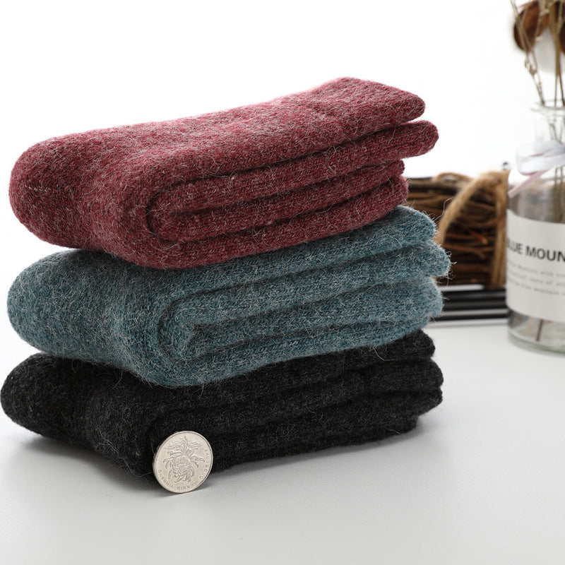 Stack of folded towels in red, blue, and black on a white surface with a coin for scale.