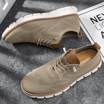 A pair of beige Hugo Ultra Comforatable Shoes on a textured surface, showcasing the side profile of the sneakers with lace-up closure.