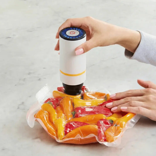 Person using a vacuum sealer to seal bell peppers on a marble surface