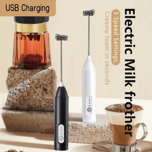 Two electric milk frothers, one black and one white, displayed next to a cup of coffee and a container of milk, with USB charging cable in the background.