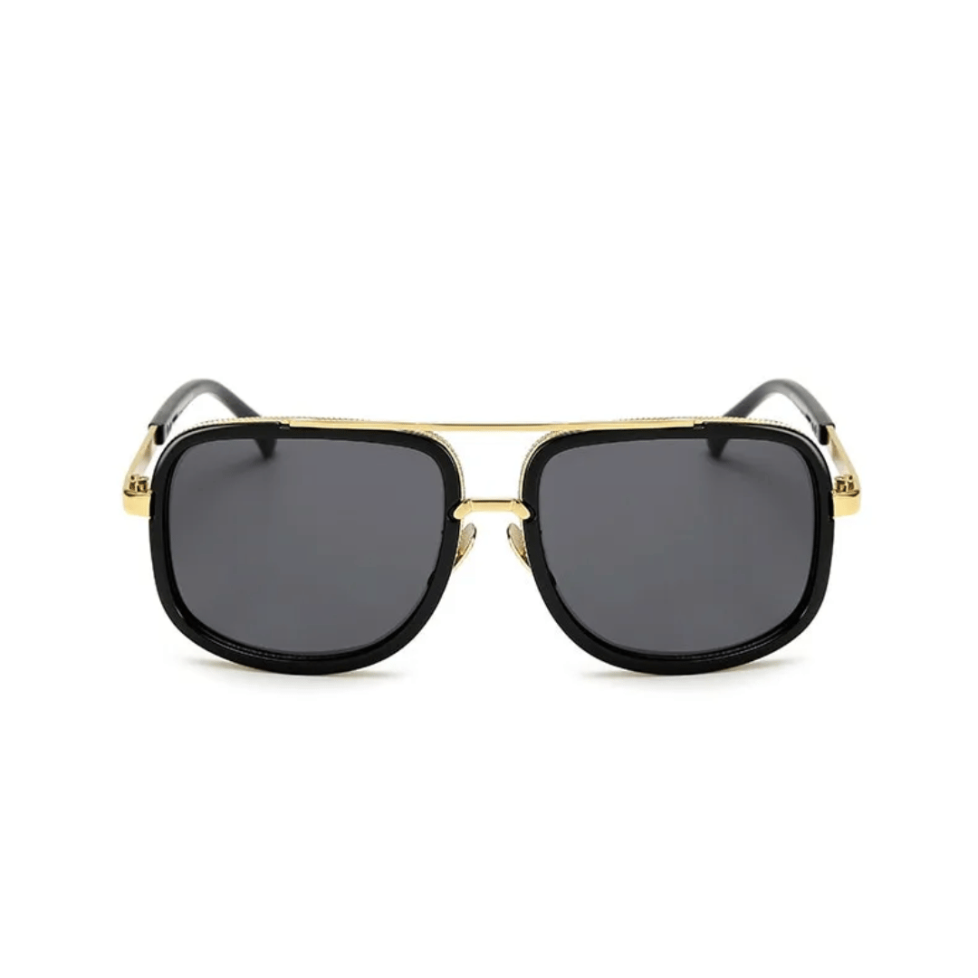A pair of aviator-style sunglasses with black plastic frames and gold metal accents. The lenses appear to be dark tinted.