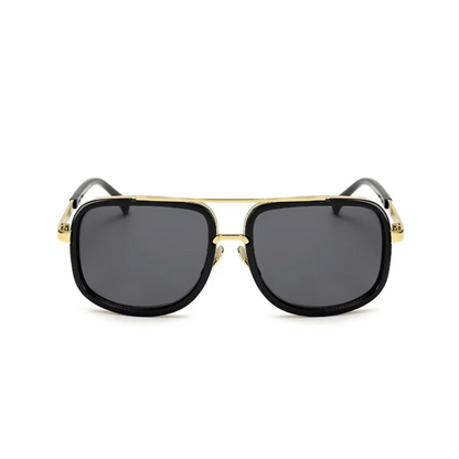 A pair of aviator-style sunglasses with black plastic frames and gold metal accents. The lenses appear to be dark tinted.