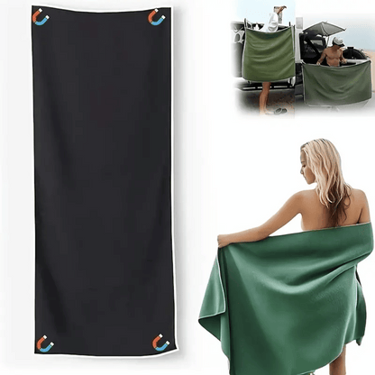 Green towel being used by a person outdoors with a black towel and stroller in the background.