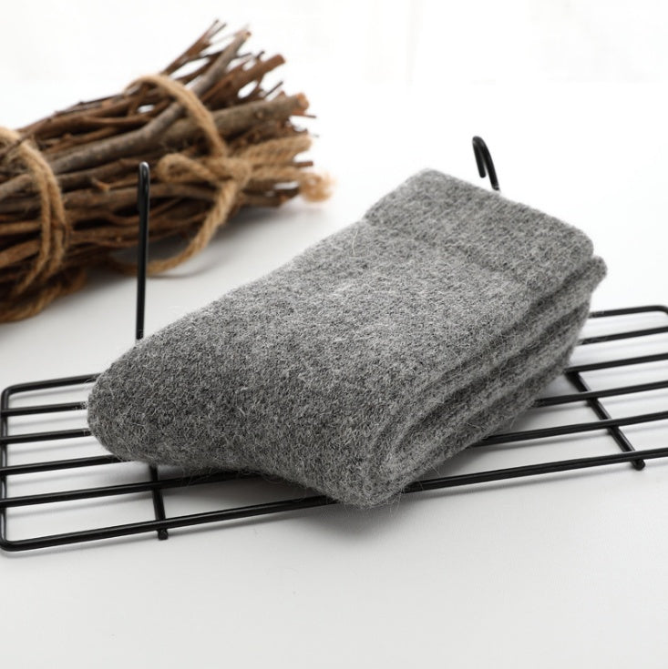 Gray socks on a black wire rack with a bundle of sticks in the background