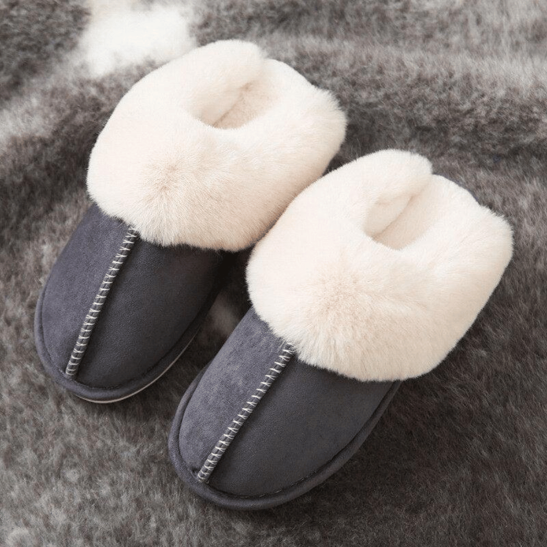 Pair of gray slippers with white fur lining on a textured surface