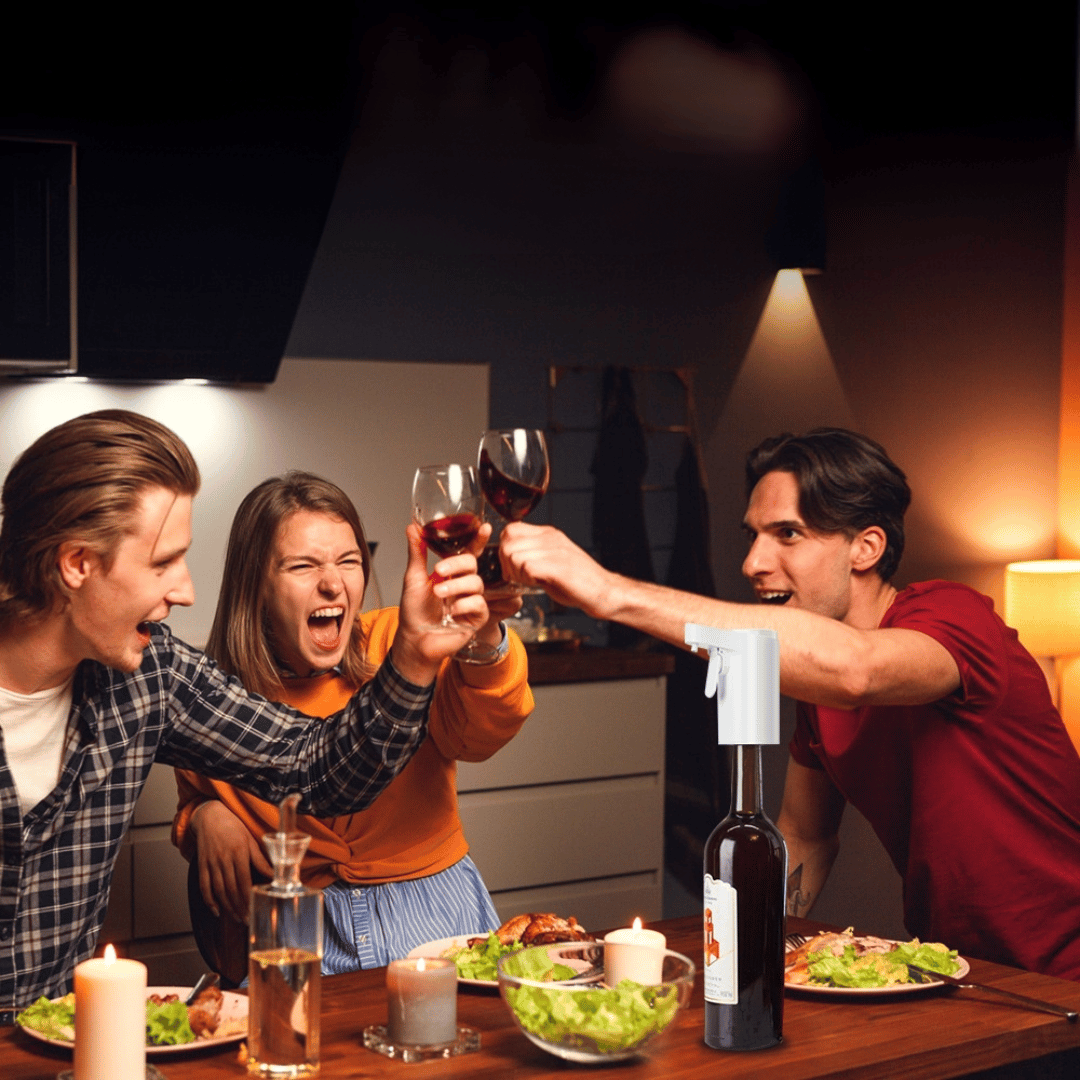 Three people toasting with wine glasses in a kitchen setting.