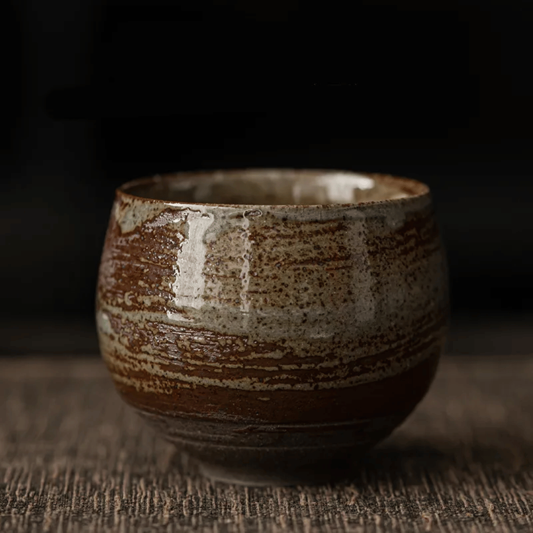 A collection of ceramic cups, likely used for tea or coffee, displayed on a table. They have a textured surface and come in various shades of brown and beige.
