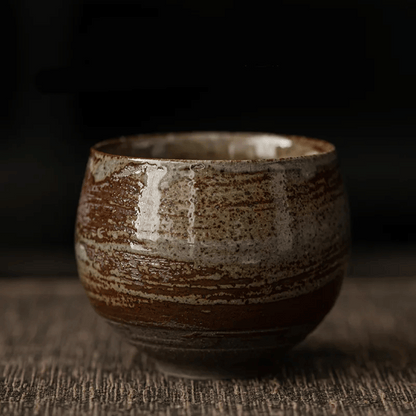 A collection of ceramic cups, likely used for tea or coffee, displayed on a table. They have a textured surface and come in various shades of brown and beige.