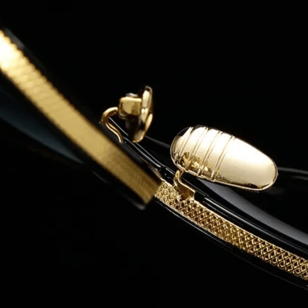 A pair of aviator-style sunglasses with black plastic frames and gold metal accents. The lenses appear to be dark tinted.