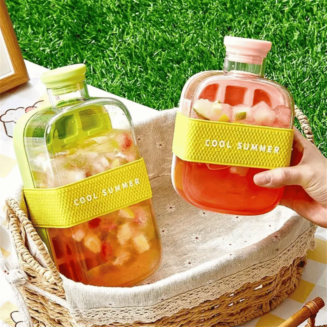 Two bottles of 'Cool Summer' juice on a woven basket with grass in the background