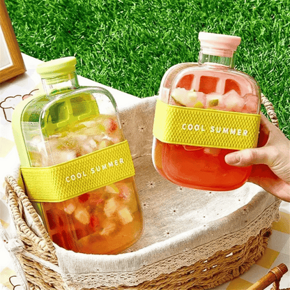 Two bottles of 'Cool Summer' juice on a woven basket with grass in the background