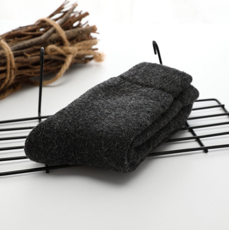 Folded dark gray socks on a wire rack with twigs in the background