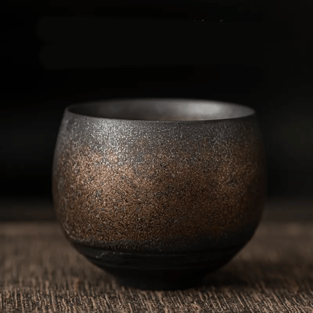 A collection of ceramic cups, likely used for tea or coffee, displayed on a table. They have a textured surface and come in various shades of brown and beige.