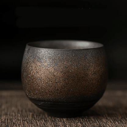 A collection of ceramic cups, likely used for tea or coffee, displayed on a table. They have a textured surface and come in various shades of brown and beige.