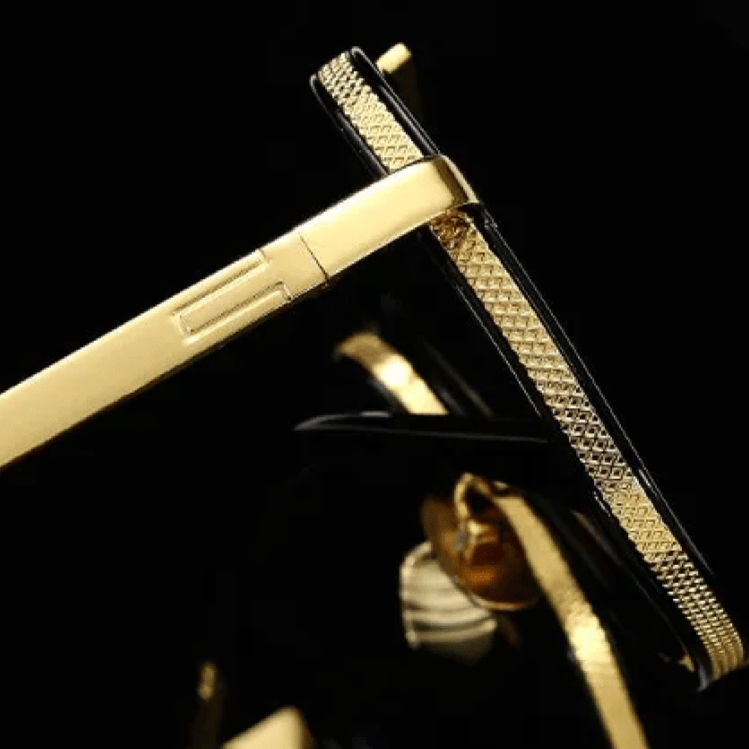A pair of aviator-style sunglasses with black plastic frames and gold metal accents. The lenses appear to be dark tinted.