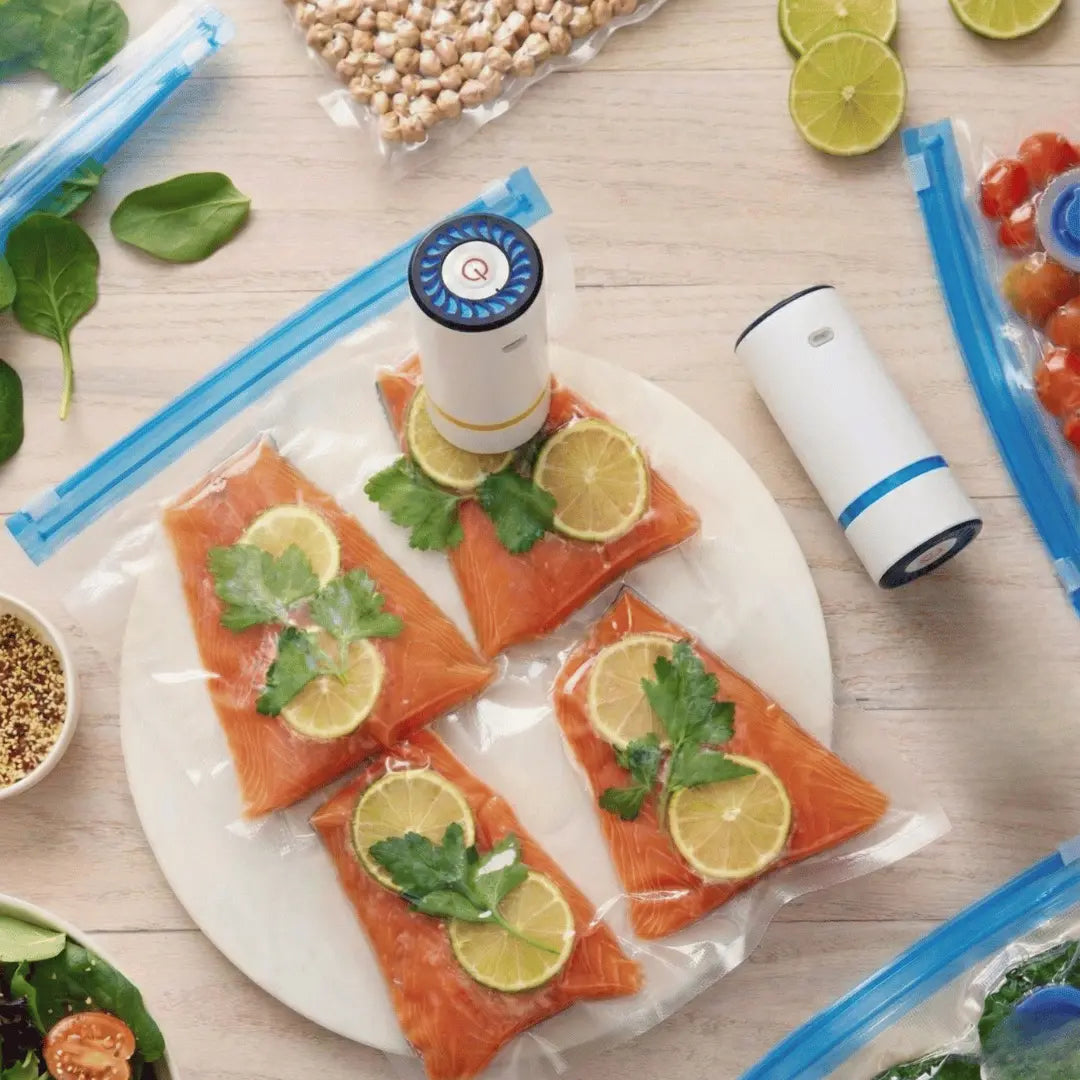 Salmon fillets with lemon and herbs on a plate, surrounded by vacuum sealers and food packaging on a wooden surface.