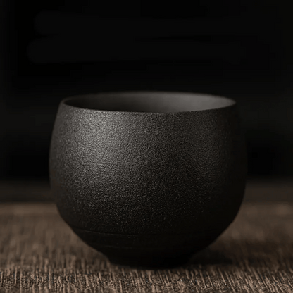 A collection of ceramic cups, likely used for tea or coffee, displayed on a table. They have a textured surface and come in various shades of brown and beige.