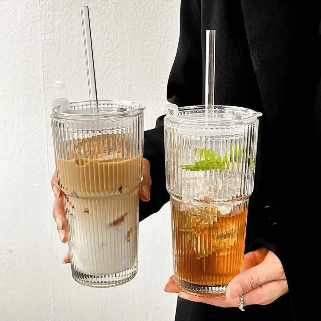 Two hands holding glasses of iced coffee and iced tea against a plain background