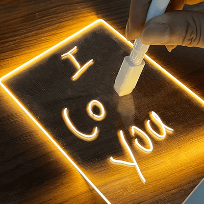 Neon sign with 'I Love You' text being written on a wooden surface.