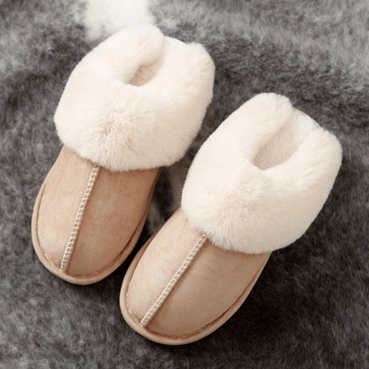 Beige slippers with fluffy white fur on a gray background