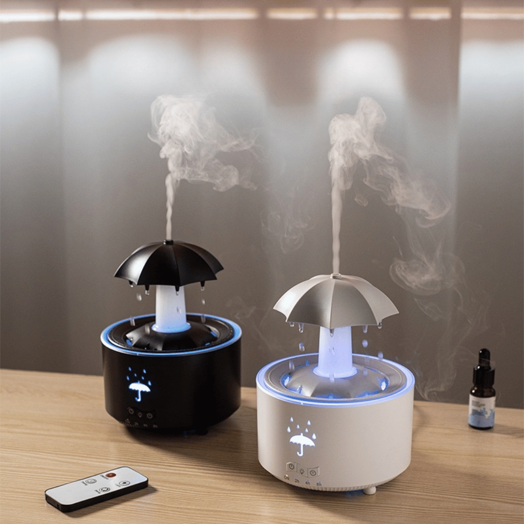 Two humidifiers shaped like umbrellas on a wooden surface with a remote control.