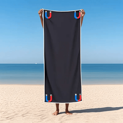 Person holding a black towel with colorful handles on a beach.
