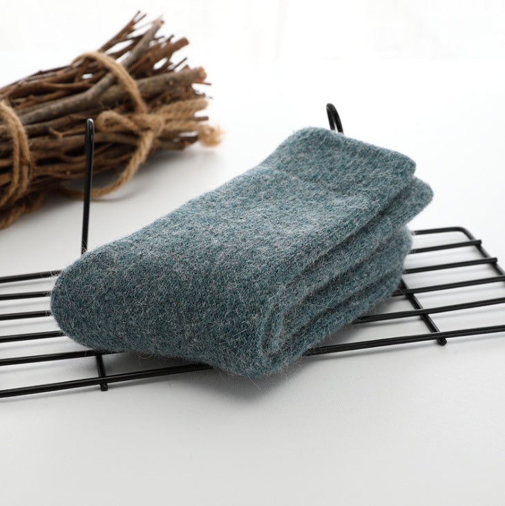Folded gray sock on a black wire rack with a bundle of sticks in the background