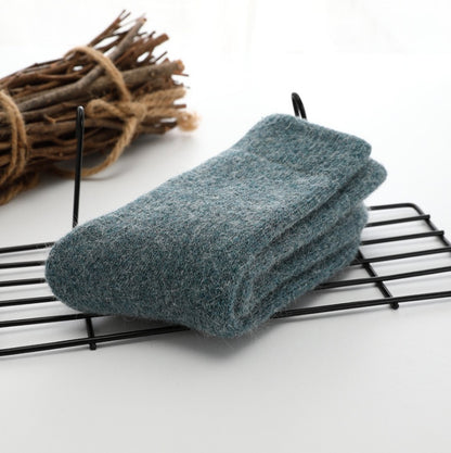 Folded gray sock on a black wire rack with a bundle of sticks in the background