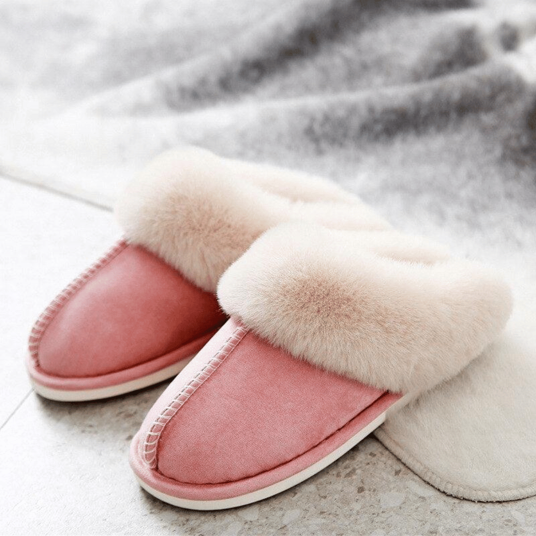 Pair of pink slippers with white fur trim on a light gray surface