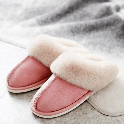 Pair of pink slippers with white fur trim on a light gray surface