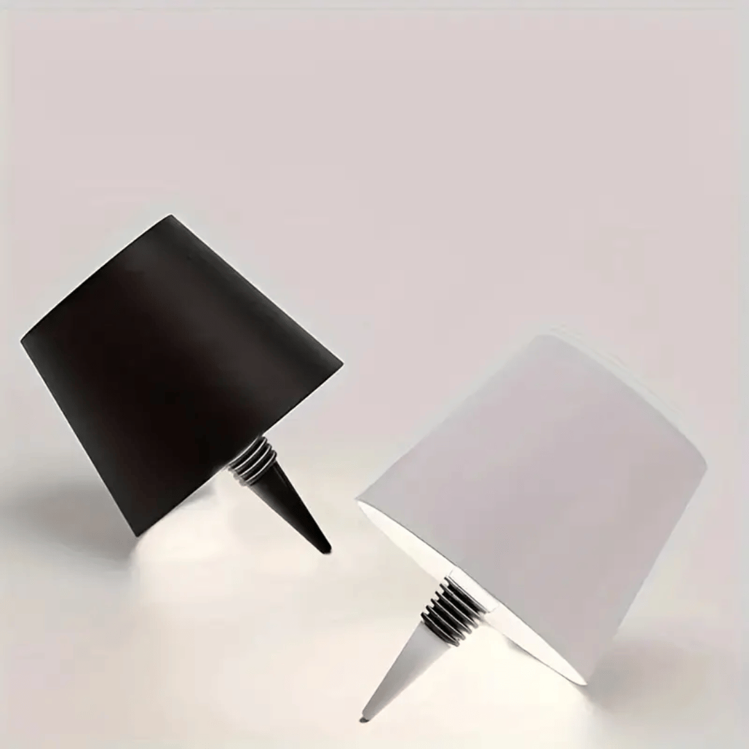 A lamp with a black shade placed on a bottle which appears to be a whiskey bottle with a label.
