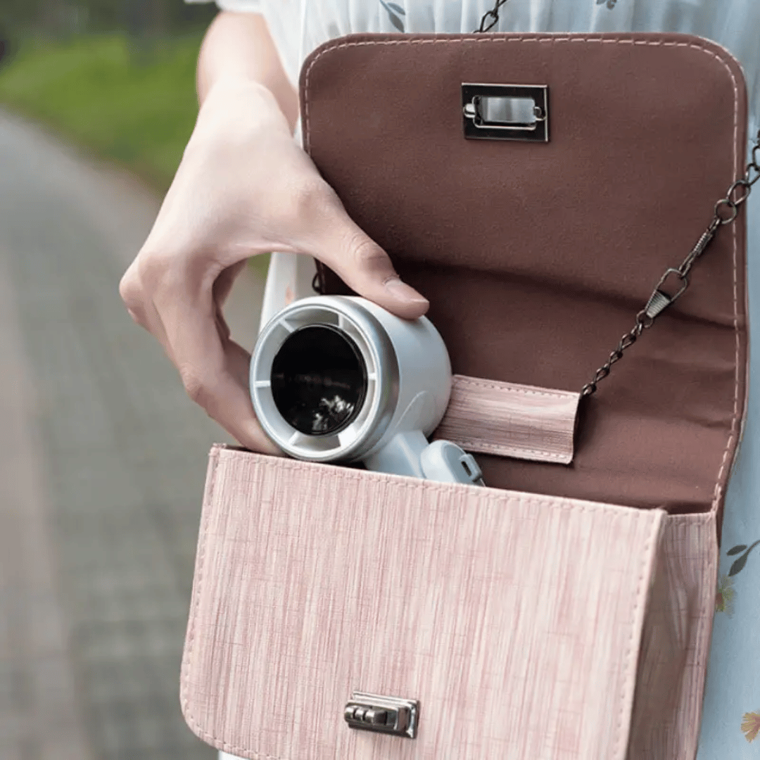 Person holding a brown handbag with a coffee cup inside, blurred background