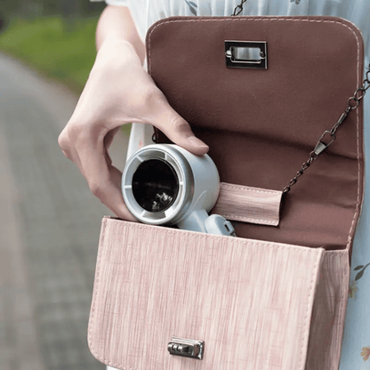 Person holding a brown handbag with a coffee cup inside, blurred background