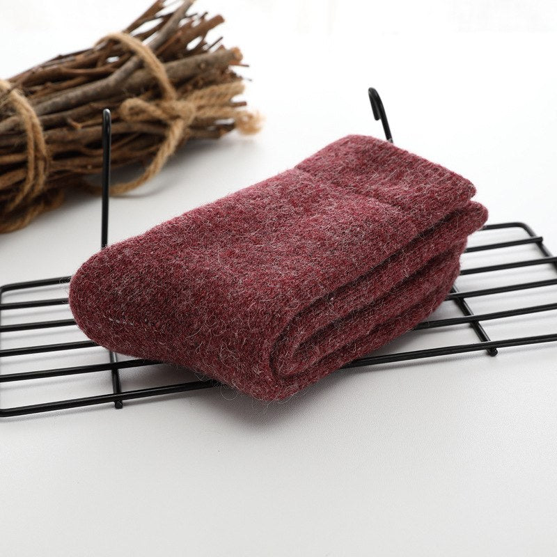 Folded maroon sock on a black wire rack with twigs in the background