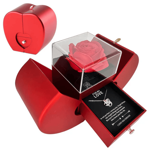A red heart-shaped gift box with a clear cover displaying a preserved rose and a necklace inside, designed for gifting.