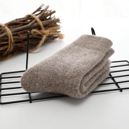 Folded brown towel on a black wire rack with twigs in the background