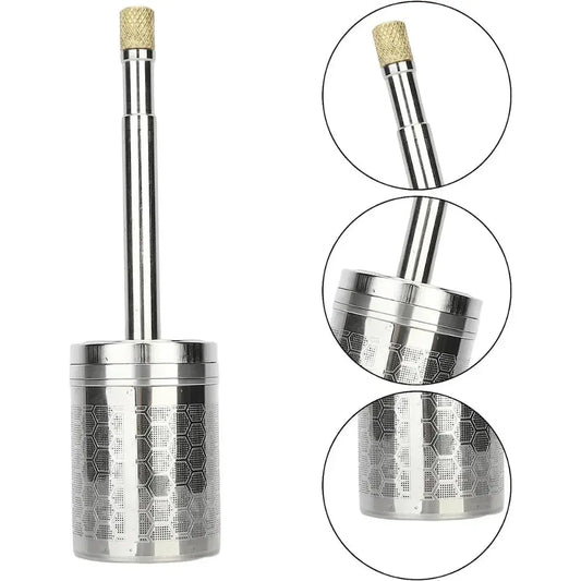 A stainless steel AromaPress lying on a bed of coffee beans, suggesting a connection to coffee brewing.